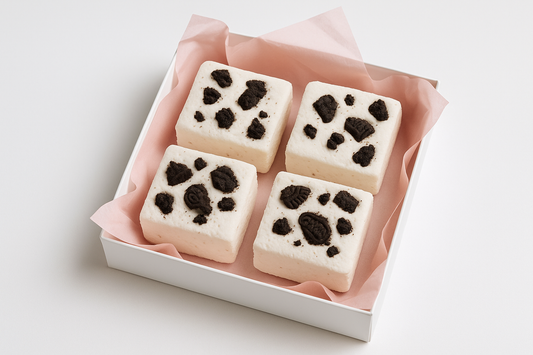 kan-du-g-ra-en-bild-p-4-mellan-stor-fyrkantigt-vit-mashmello-med-oreos-bitar-på i en vit gift box och med rosa gift papper under med-vit-background