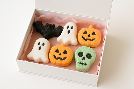 kan du göra en bild på en vit gift box med rosa gift papper under som innehåller 6 st marsmellos 1. fläddermoss svart , 2. gost vit 3. pumpkin ansikte orange 4. dödskalle grön blandad med vit bakgrund